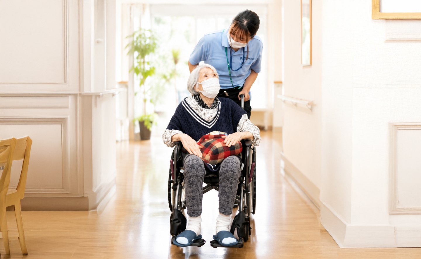 廊下で車椅子のご入居者様に付き添うスタッフ